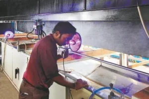 A man working in a shop with a large amount of glass