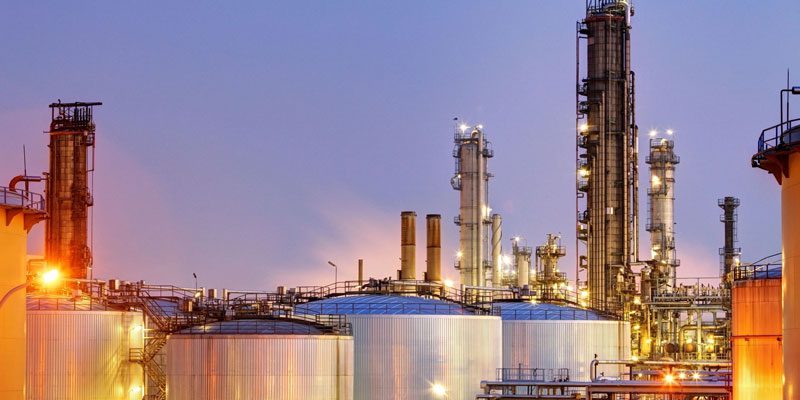 A group of large oil tanks in front of a factory.